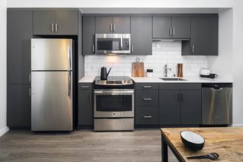 a kitchen with stainless steel appliances and black cabinets at Delphine on Diamond, California, 94131